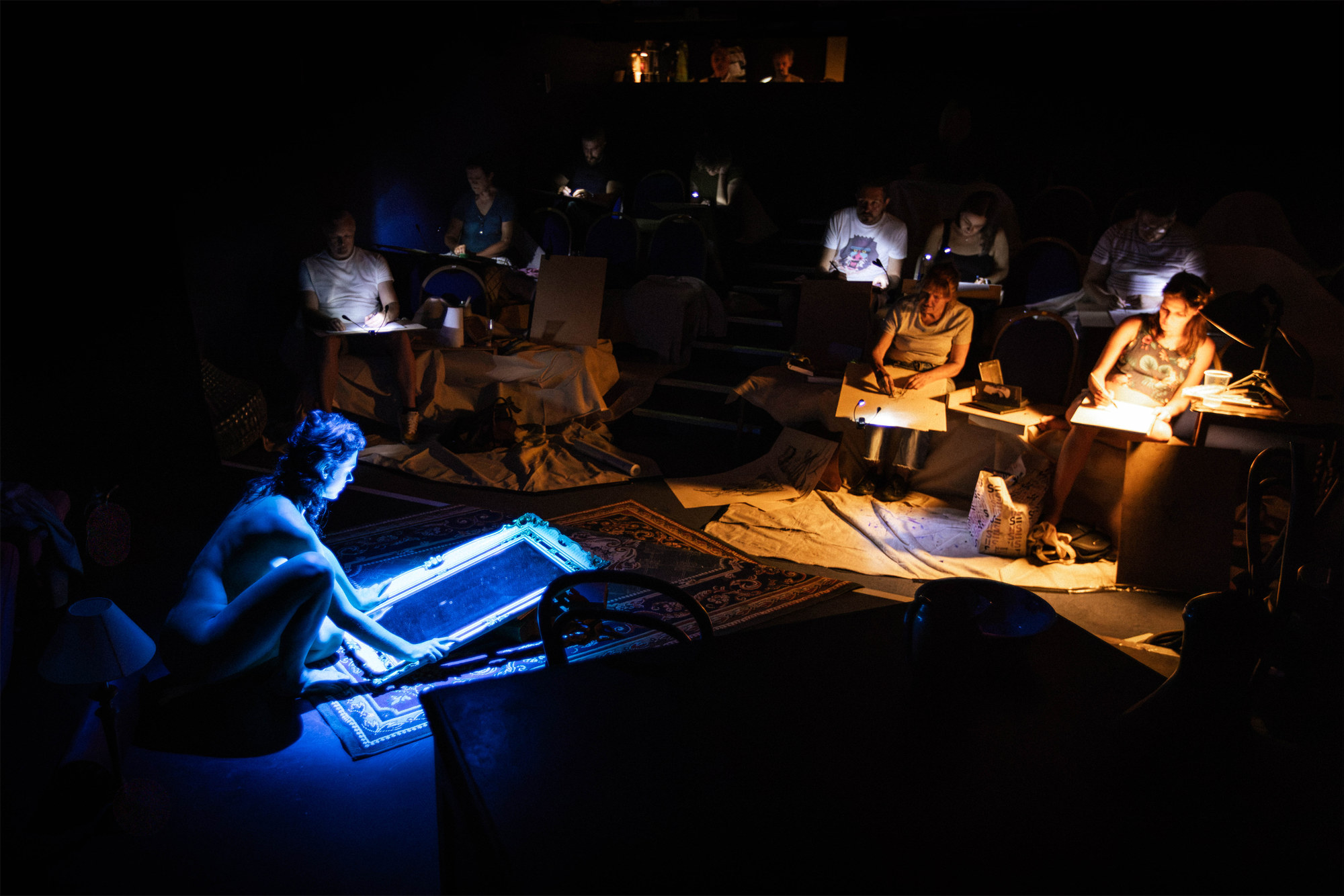 Audience drawing a performer illuminated in blue during Theatre Life Drawing at Northenden Players Theatre.